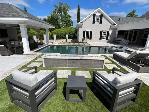 Backyard pool surround with turf, stone pavers and modern lounge seating