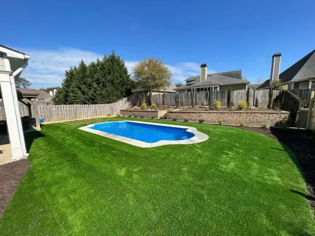 Backyard turf with a pool and stone wall
