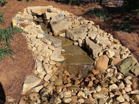 Boulder and river-rock waterfall stream in a mulched garden