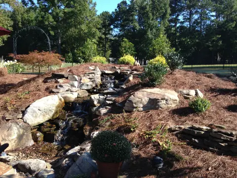 Boulder waterfall and stream beside a mulched bed
