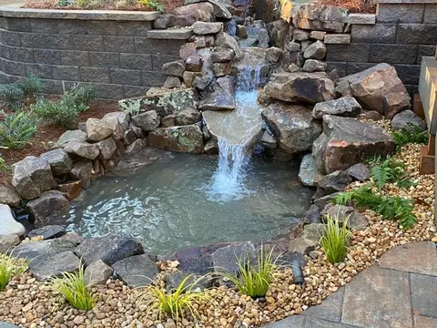 Boulder waterfall into a small pond with a paver edge