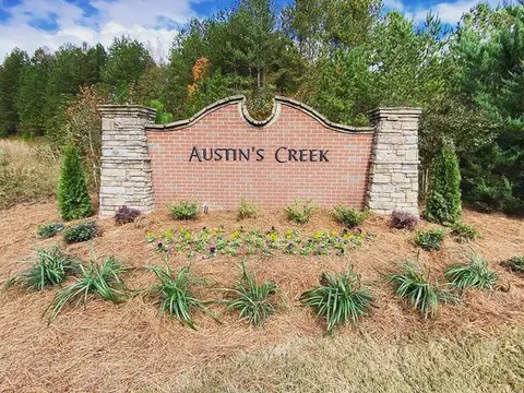 Brick and stone Austin’s Creek entrance sign with pine-straw beds, grasses and seasonal flowers