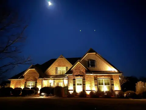 Brick and stone home lit from below under a night sky
