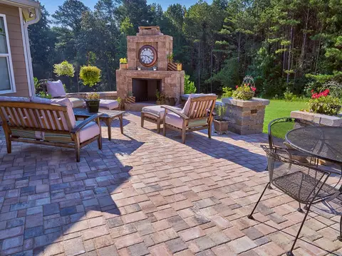 Brick paver patio with an outdoor fireplace with a clock and seating