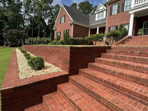 Brick steps and a retaining wall with a rock-lined bed