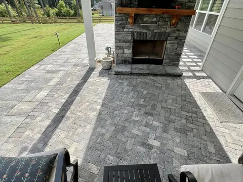 Covered porch with a stone fireplace and a paver floor