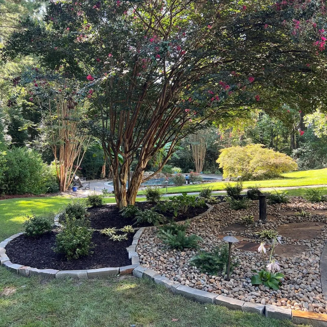 Mulched bed and river-rock garden with stepping stones and a stone border