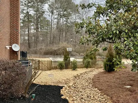 Dry creek bed of river rock beside a mulched bed along a house