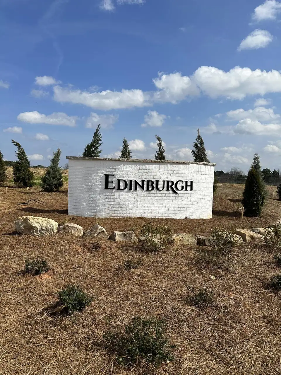 Edinburgh community sign in a mulched bed with boulders and young evergreens