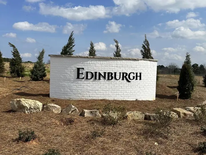 Edinburgh community sign in a mulched bed with boulders and young evergreens