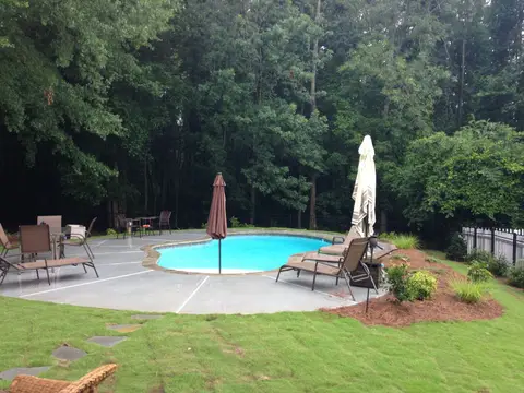 Fiberglass pool with a concrete deck and a patio set on a new lawn