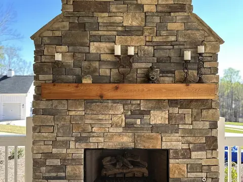 Floor-to-ceiling stacked stone fireplace on a covered flagstone patio