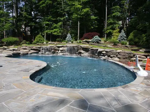 Freeform pool with a boulder waterfall and a flagstone deck