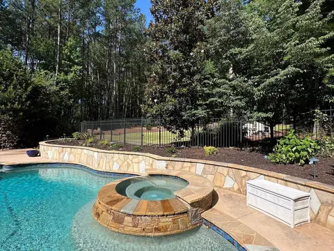Freeform pool with a stone-edged spa, a wall and a landscaped bed