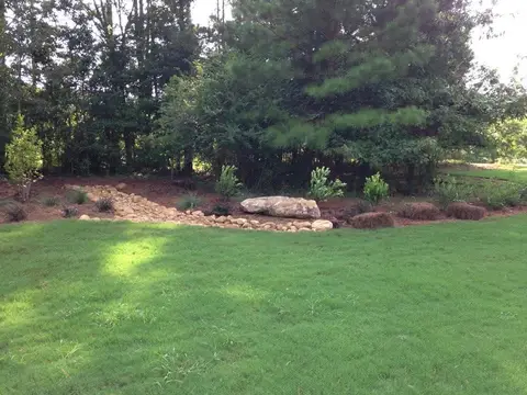 Fresh sod lawn with boulders and a mulched planting bed