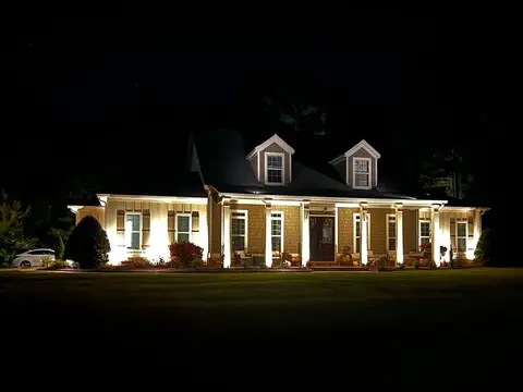 Home lit at night with uplighting along the porch
