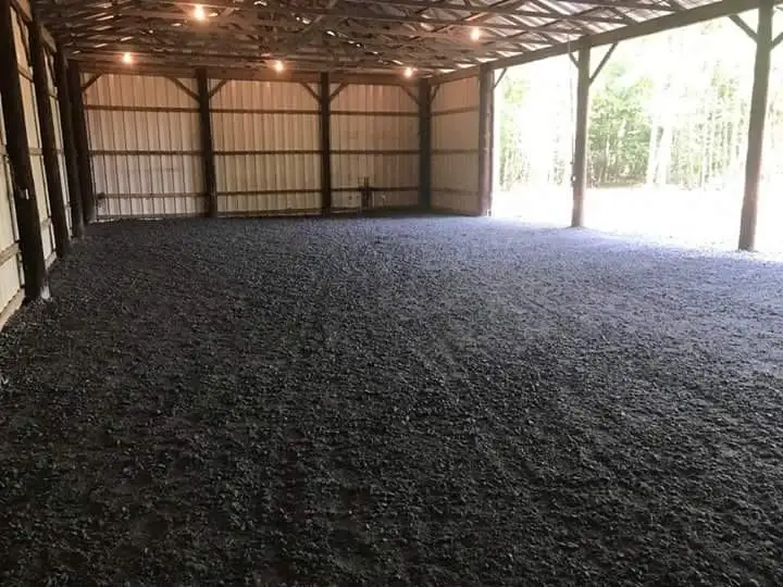 Interior of a large open-sided building with a freshly prepared dark footing surface