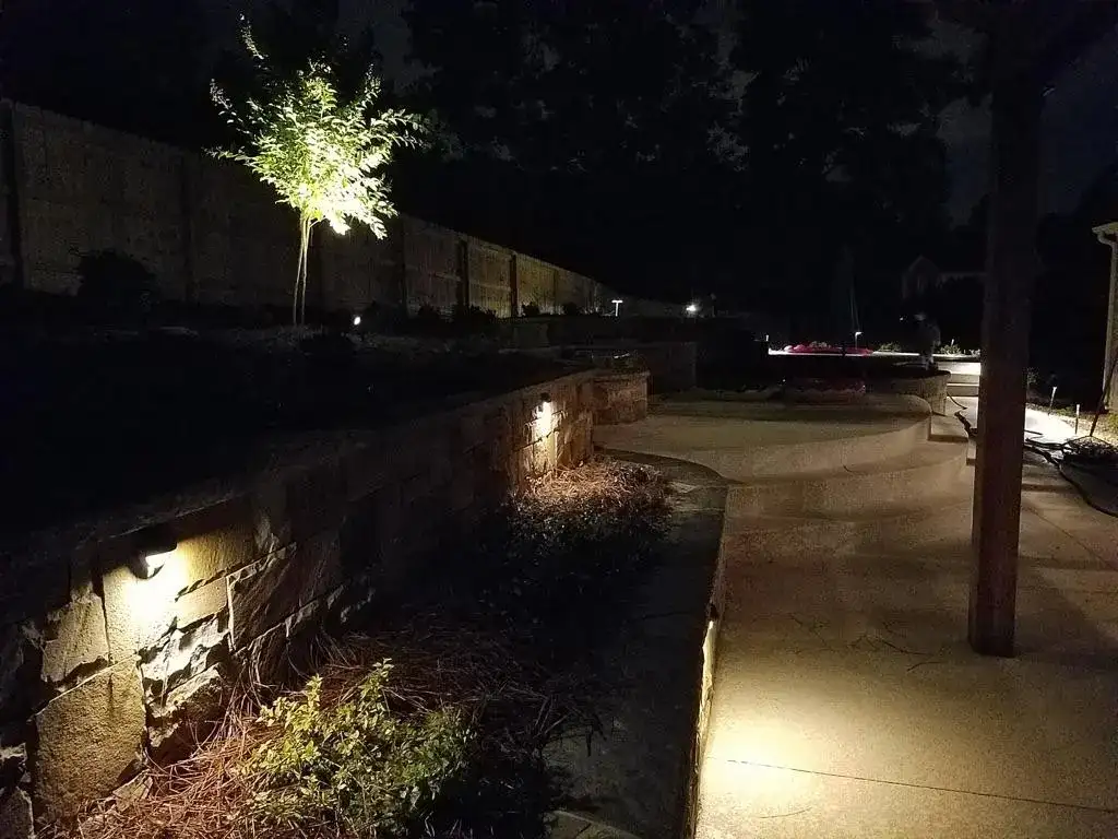 Stone walls and patio lit at dusk by landscape lighting