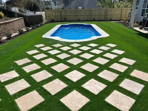 Large-format paver stepping stones in turf beside a pool