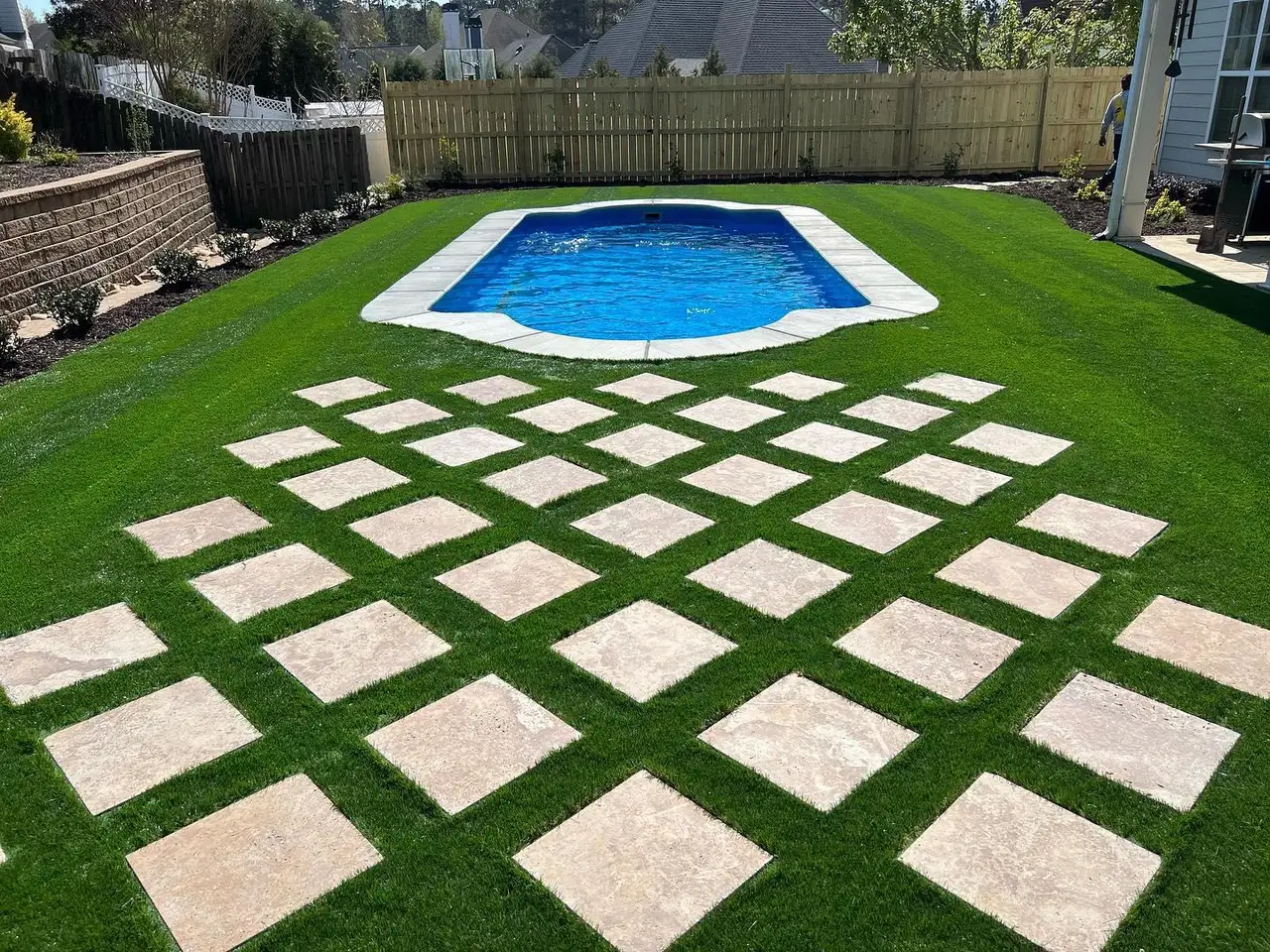Large-format paver stepping stones in turf beside a pool
