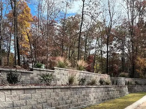 Long segmental block retaining wall beside a driveway in autumn