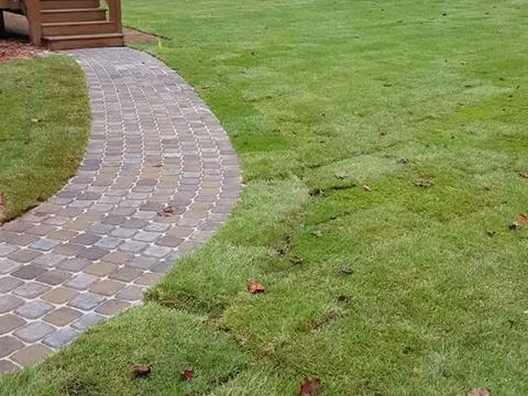 New sod and a paver path beside a deck