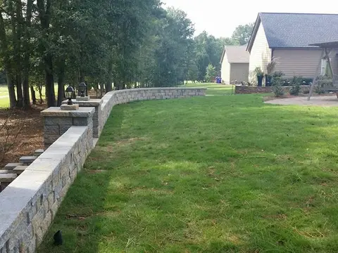 New sod lawn beside a block retaining wall and a patio
