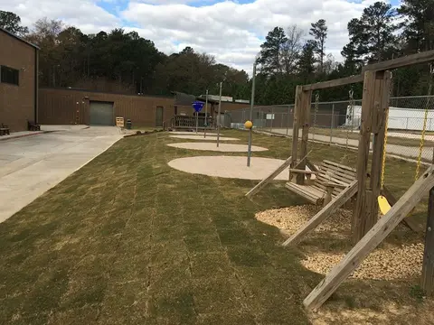Newly sodded play area with a swing set beside a building