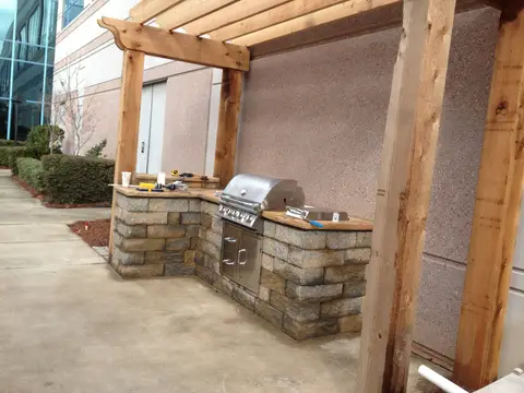 Outdoor kitchen with a built-in grill under a cedar pergola in an office courtyard