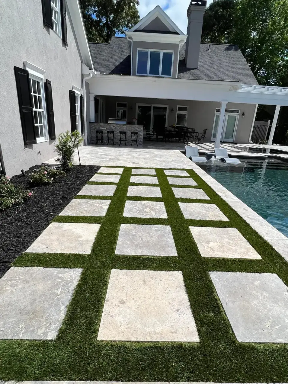 Limestone pavers set in turf beside a pool