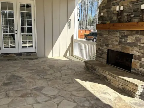Stacked stone fireplace with a wood mantel on a covered patio