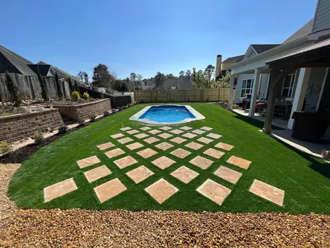 Stone stepping pavers set in turf leading toward a pool