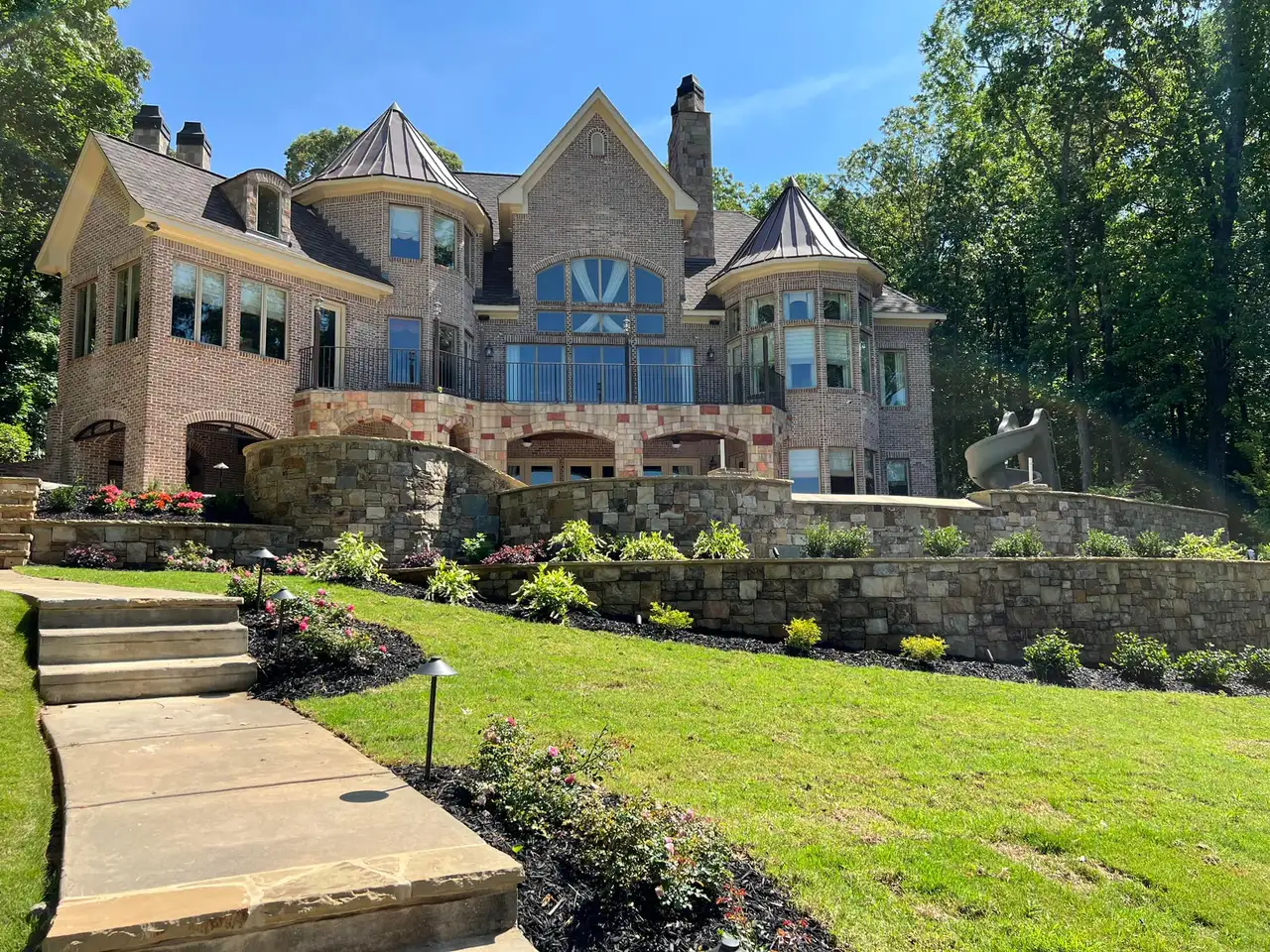 Brick and stone estate with terraced stone retaining walls and planting beds