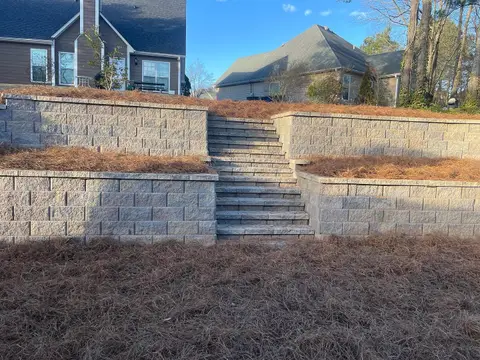Tiered block retaining walls with steps in a backyard
