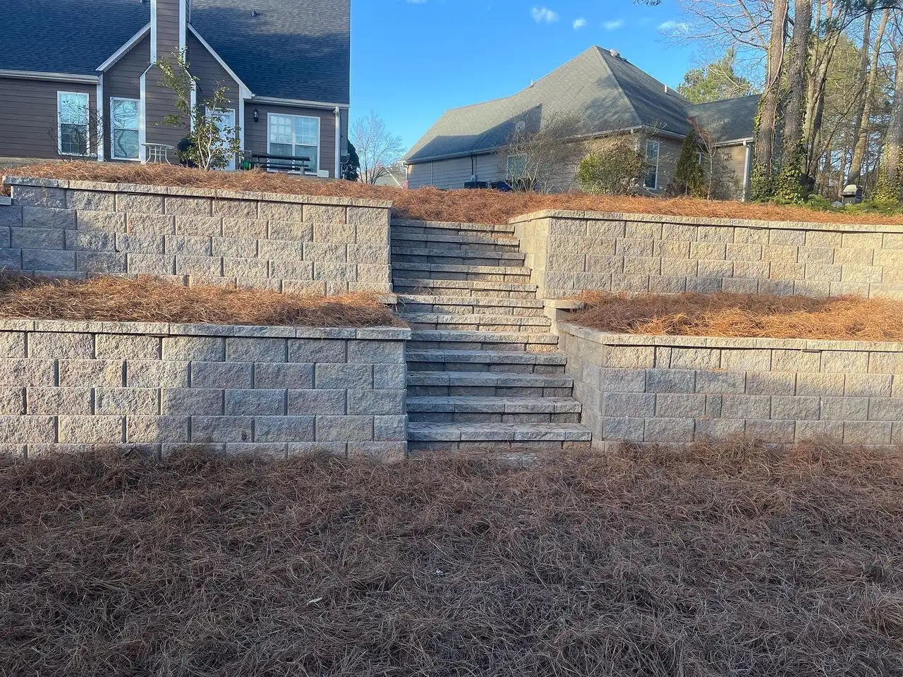 Tiered block retaining walls with steps in a backyard